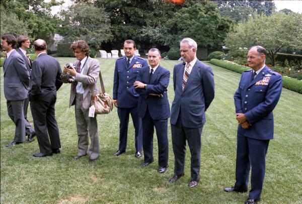 General David Jones, Assistant Secretary of Defense William Clements, Secretary Schlesinger, General George Brown, and photographers attend Brent Scowcroft's promotion ceremony to Lieutenant General in the White House Rose Garden, 9/5/1974.